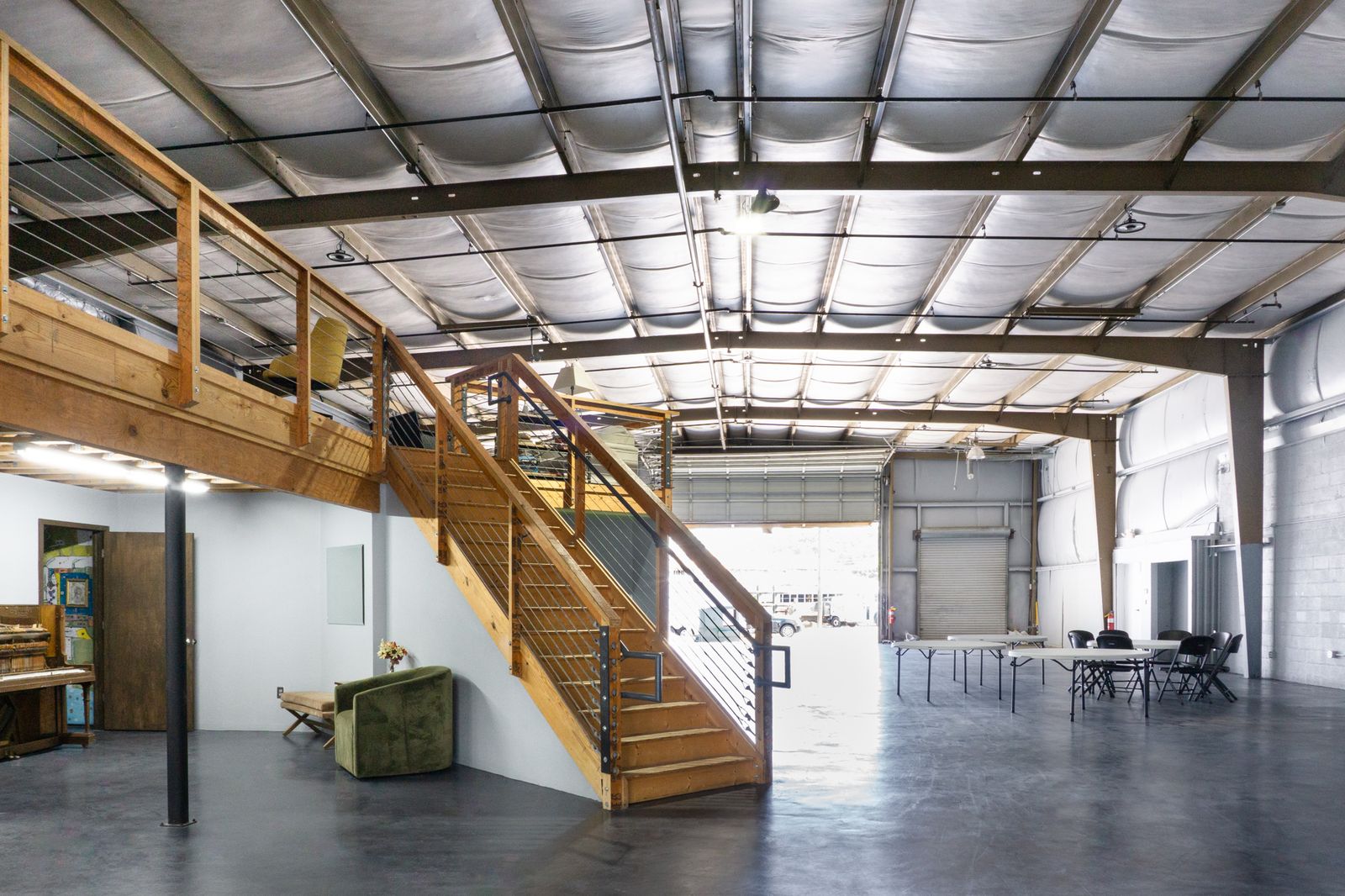 Wood staircase rising to the loft inside the Big Room with an open bay door
