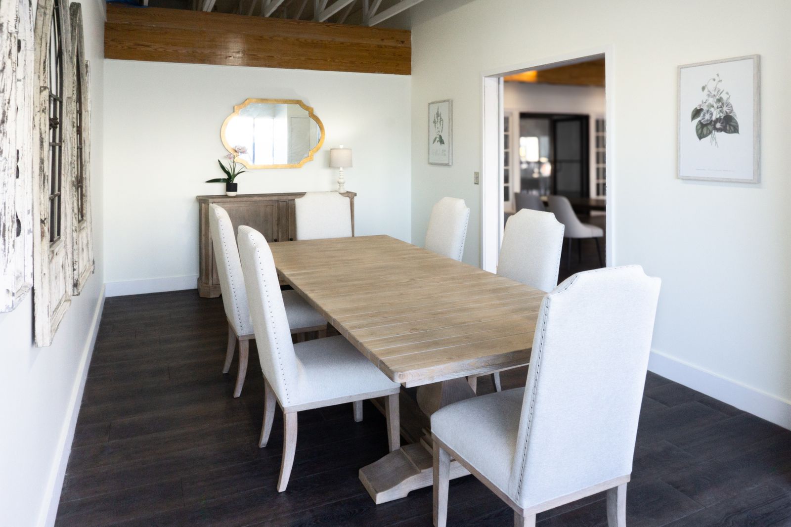Angled view of the signing table beneath a warm wood beam with a gold mirror and art