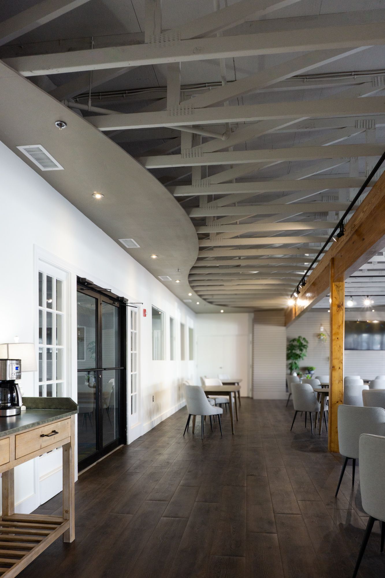 Long interior establishing shot with exposed truss ceiling and cafe-style seating