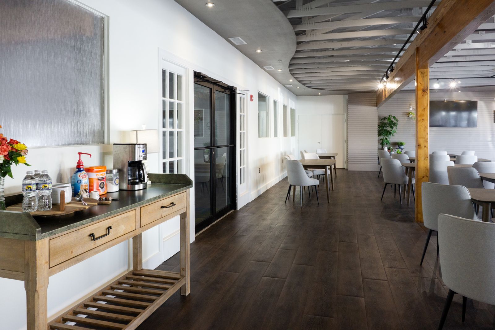 Open interior gathering space with a wall of windows and arranged tables and chairs